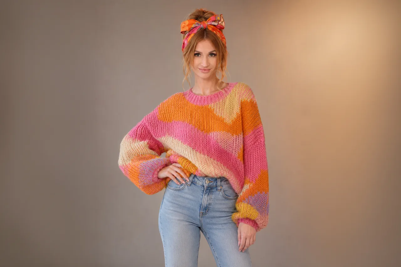 Bamby Doll wearing a colorful sweater and jeans in a studio portrait